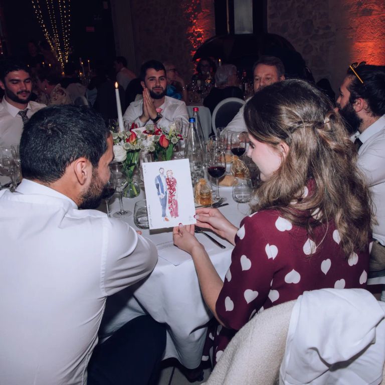 Invités découvrant leur portrait personnalisé réalisé à l'aquarelle pendant la réception de mariage.