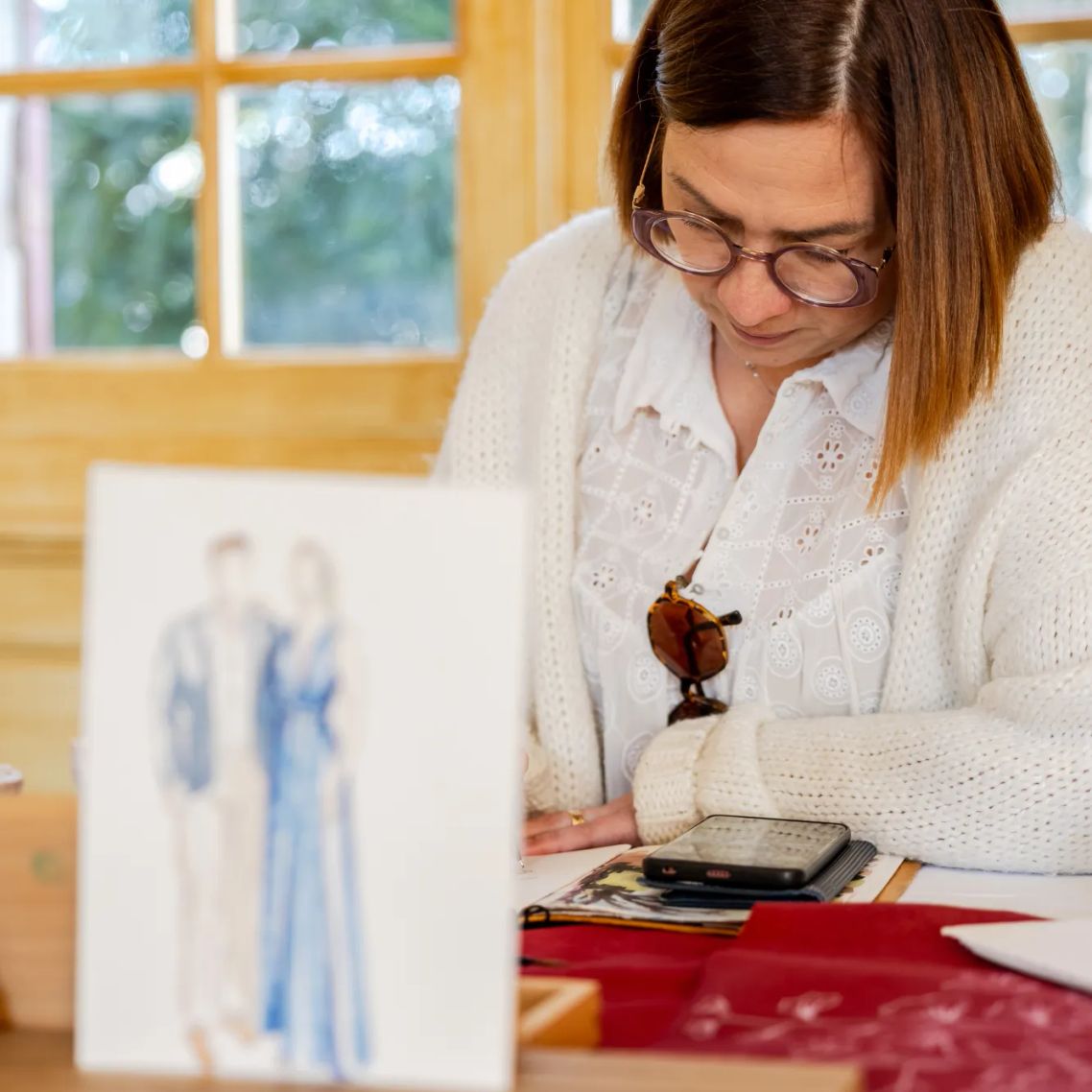 Préparation d'illustrations à l'aquarelle dans l'atelier d'une artiste spécialisée dans les souvenirs de mariage personnalisés.